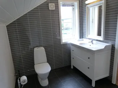 a bathroom with a toilet and a sink and a window at Loftesnes in Sogndal