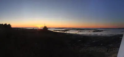 a sunset over the water with a tree in the foreground at Finnøya with 180* Atlantic veiw in Finnøy
