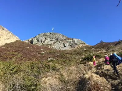 a group of people walking up a hill with luggage at Finnøya with 180* Atlantic veiw in Finnøy