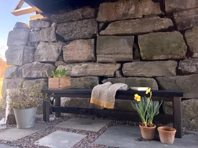 a bench sitting in front of a stone wall at Drolsum Gård in Vikersund