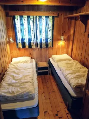 two beds in a small room with wooden walls at Hogstul Hytter - Skojestua - 2 Bedroom Cottage in Tuddal