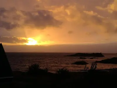 a sunset over the ocean with the sun setting at Kuvågen 23 in Vågenes