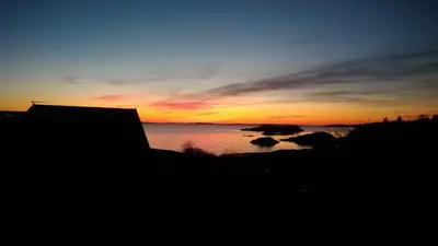 a sunset over a body of water with rocks in it at Kuvågen 23 in Vågenes