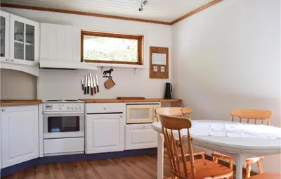 a kitchen with white cabinets and a table and chairs at 4 Bedroom Beautiful Home In Steinstø in Steinstø