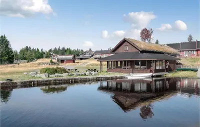 a building with a thatched roof next to a lake at Fjellstua C3, Leil 202 in Sjusjøen