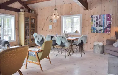 a dining room with a table with chairs and a couch at Three-Bedroom Holiday Home In Hovet in Hovet