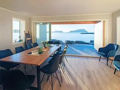 a dining room with a table and chairs and a large window at 10 person holiday home in Brattvåg in Brattvåg