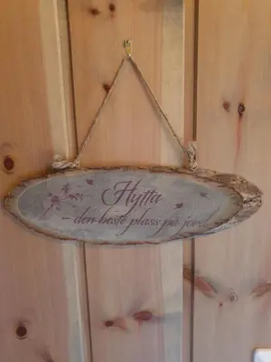a sign is hanging on a wooden wall at Koselig familiehytte sentralt på Skeikampen til leie in Svingvoll