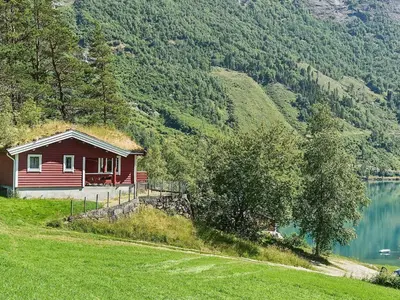 a small red house on a hill next to a lake at 8 person holiday home in olden in Olden