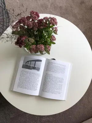a book on a white table with a vase of flowers at Olsens Pensjonat in Veiholmen