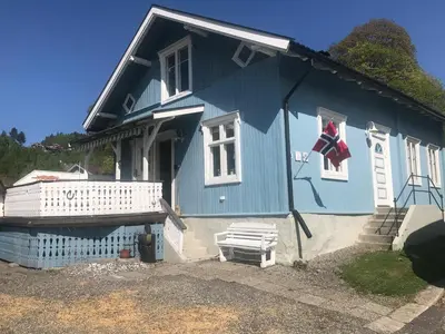 a blue house with a flag on the front of it at Charming Lakeside House with sauna in Lillehammer