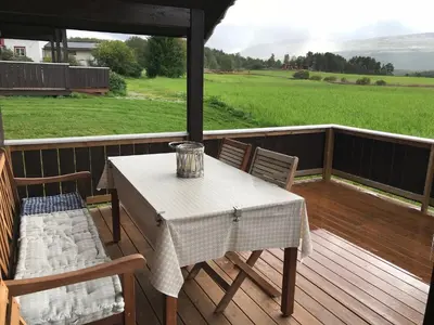 a table and chairs on a deck with a view of a field at Roste Hyttetun og Camping in Os