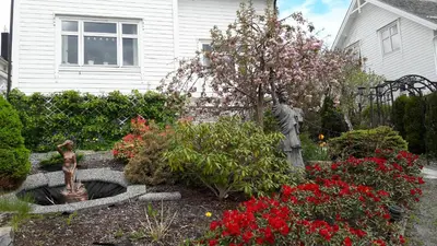 a garden with a statue and flowers in front of a house at Huset på hauen in Volda
