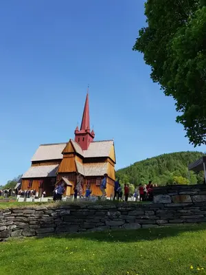 a large wooden church with a steeple in a field at Lille Randklev Gæstehus in Ringebu