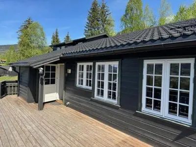 a black house with white windows on a wooden deck at Sørlia hytte in Hafjell