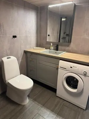 a bathroom with a toilet and a sink and a washing machine at Sørlia hytte in Hafjell