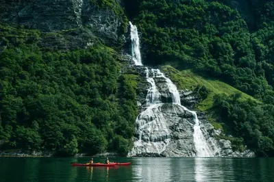 a group of people in a red boat in front of a waterfall at Hotel Union Geiranger Bad & Spa in Geiranger