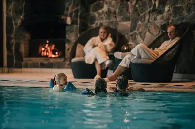 a family in a swimming pool in front of a fireplace at Hotel Union Geiranger Bad & Spa in Geiranger