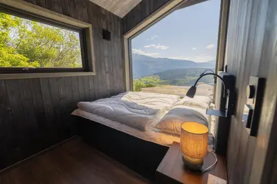 a bed in a room with a large window at Hardanger Panorama Lodge in Ulvik