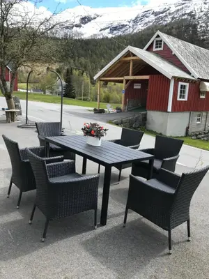 a picnic table with chairs and a vase of flowers at Josygaard in Austefjorden