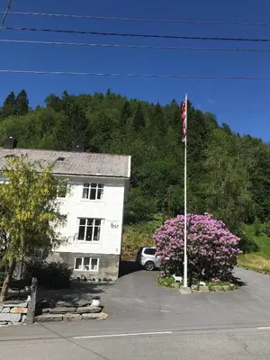 a flag pole in front of a white building at Josygaard in Austefjorden