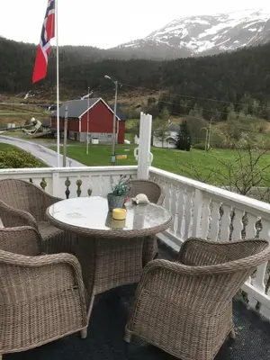 a table and chairs on a balcony with a snow covered mountain at Josygaard in Austefjorden