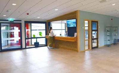 a woman standing at a counter in a lobby at Raulandsakademiet in Rauland
