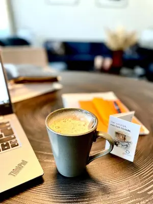 a cup of coffee sitting on a table next to a laptop at Dreges Hotell - by Classic Norway Hotels in Stranda