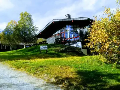 a building on a hill with a sign in the grass at Dombåstun Motel in Dombås