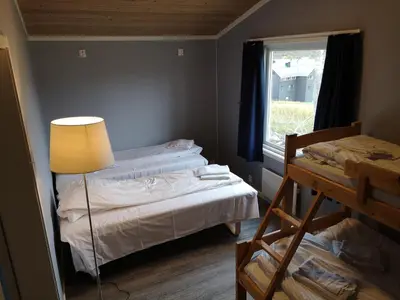 a bedroom with two beds and a lamp and a window at Dombåstun Motel in Dombås