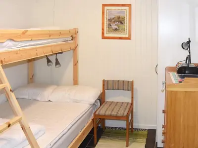 a bedroom with two bunk beds and a chair at Seaside Serenity in Leirvik-By Traum in Bø