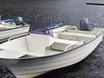 a white boat is docked in the water at Seaside Serenity in Leirvik-By Traum in Bø