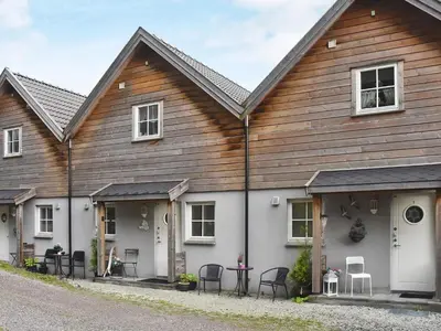 a house with a wooden roof and black chairs at Seaside Serenity in Leirvik-By Traum in Bø