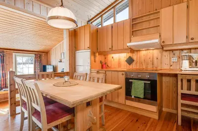 a dining room with a table and a kitchen at Bitigrenda I in Beitostøl