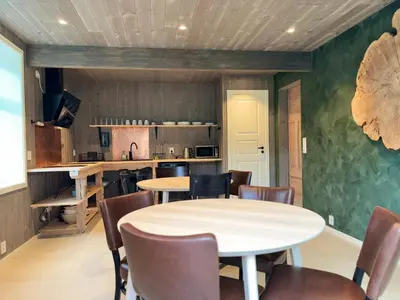 a dining room with tables and chairs and a kitchen at Brekke Gard Hostel in Flåm
