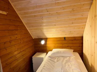 a small bedroom with a bed in a wooden room at Brekke Gard Hostel in Flåm