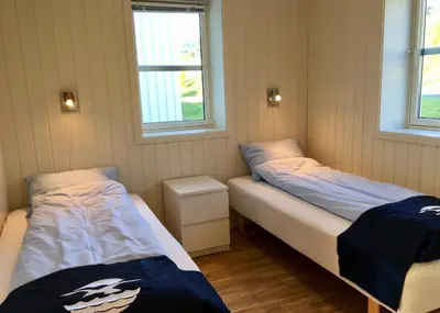 two beds in a room with two windows at Hindrum Fjordsenter in Vannvikan