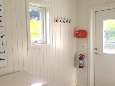 a white bathroom with a window and a bench at Hindrum Fjordsenter in Vannvikan
