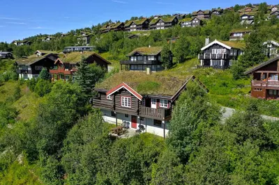 a group of houses on a hill with trees at Ideal For Families 6 Bedrooms, Hot Tub And Sauna in Beitostøl