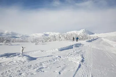 two people are skiing down a snow covered slope at Ideal For Families 6 Bedrooms, Hot Tub And Sauna in Beitostøl