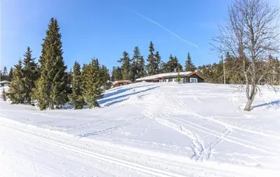 a snow covered slope with a house in the background at Three-Bedroom Holiday Home In Sjusjoen in Sjusjøen