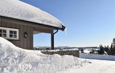 a house covered in snow next to a building at 3 Bedroom Stunning Home In Sjusjøen in Sjusjøen