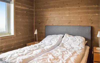 an unmade bed in a room with wooden walls at 3 Bedroom Beautiful Home In Sjusjøen in Sjusjøen