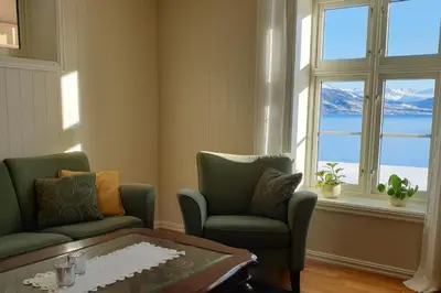 a living room with two chairs and a table and windows at Irenegarden - Panorama apartment in Lauvstad