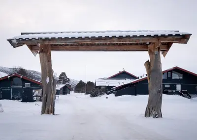 a wooden pavilion in the snow in front of buildings at Supersentralt ski inn ski out in Geilo