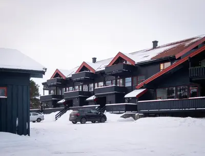 a snow covered parking lot in front of a lodge at Supersentralt ski inn ski out in Geilo