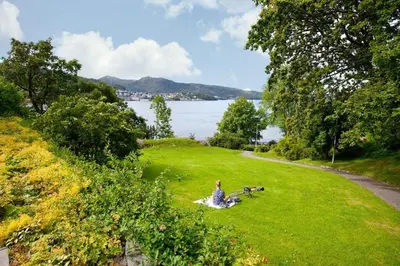 a woman sitting in the grass with two dogs at Apartment Bergen Central in Bergen