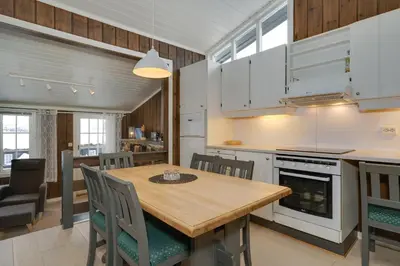 a kitchen and dining room with a wooden table and chairs at Bitigrenda G in Beitostøl