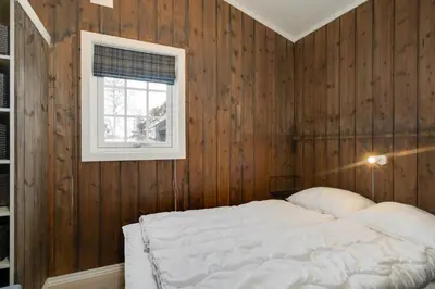 a bedroom with wooden walls and a bed with a window at Bitigrenda K in Beitostøl