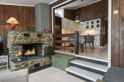 a living room with a stone fireplace and a staircase at Bitigrenda F in Beitostøl